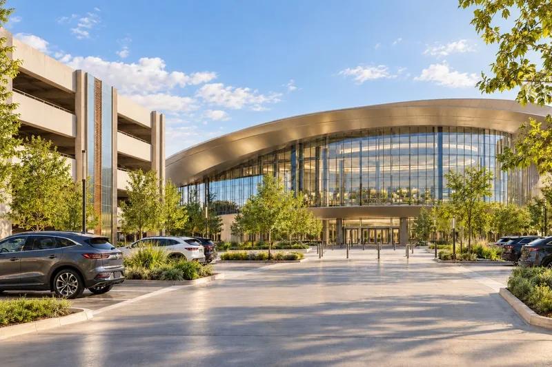 A contemporary arena beside its parking structure, in daylight. A generated scene.